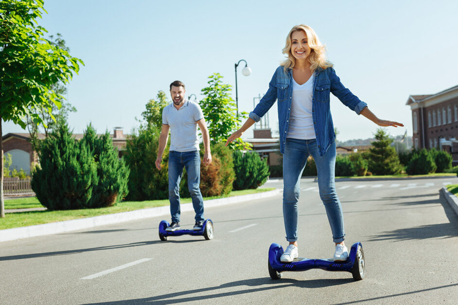 Man and woman are riding with 2-wheel hoverboards while having a lot of fun