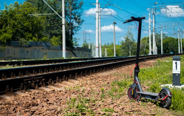 Electric scooter Xiaomi M360 standing on the grass next to the railway.