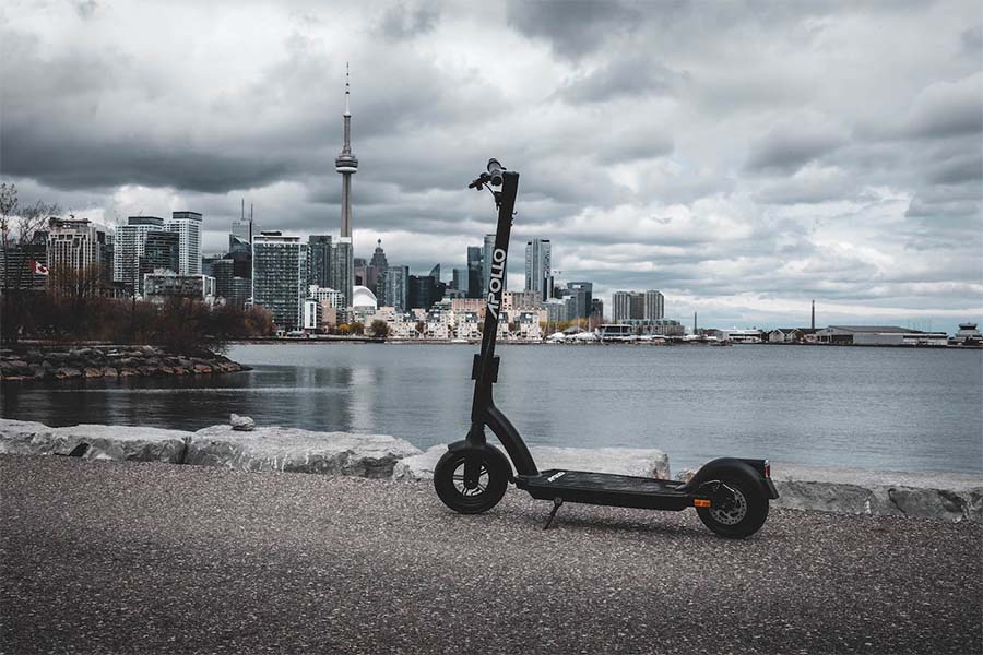 Affordable electric scooter Apollo Air standing next to the sea.