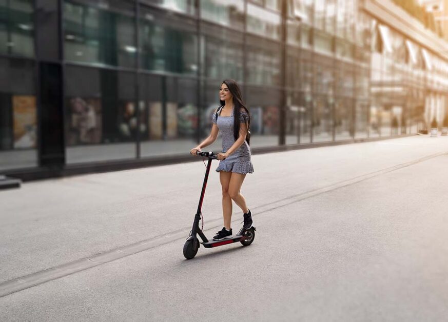 a pretty woman is riding with an electric scooter