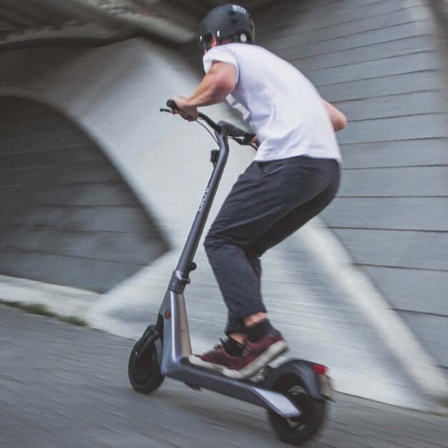 A man rides an electric scooter uphill.