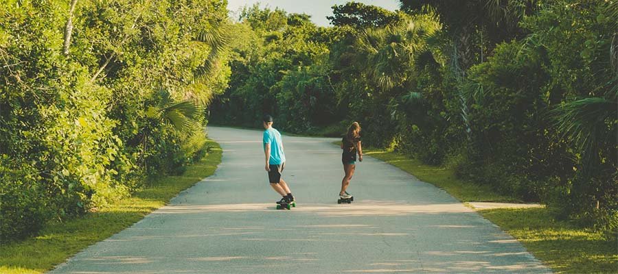 2 men are riding with electric skateboards