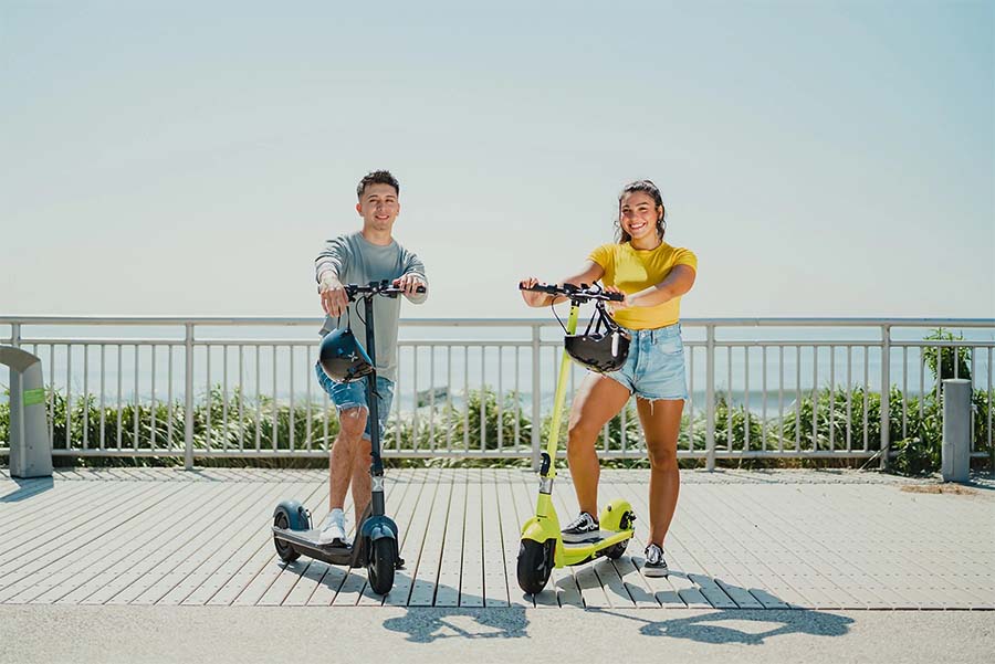 Boy and girl posing with electric scooters.