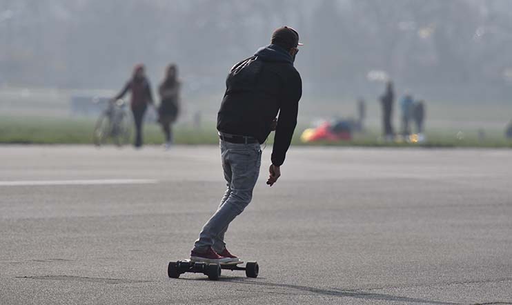 man is riding with an electric skateboard.