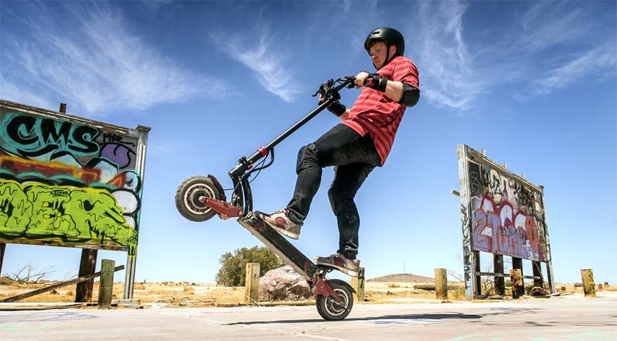 man with safety gear on doing tricks with an electric scooter
