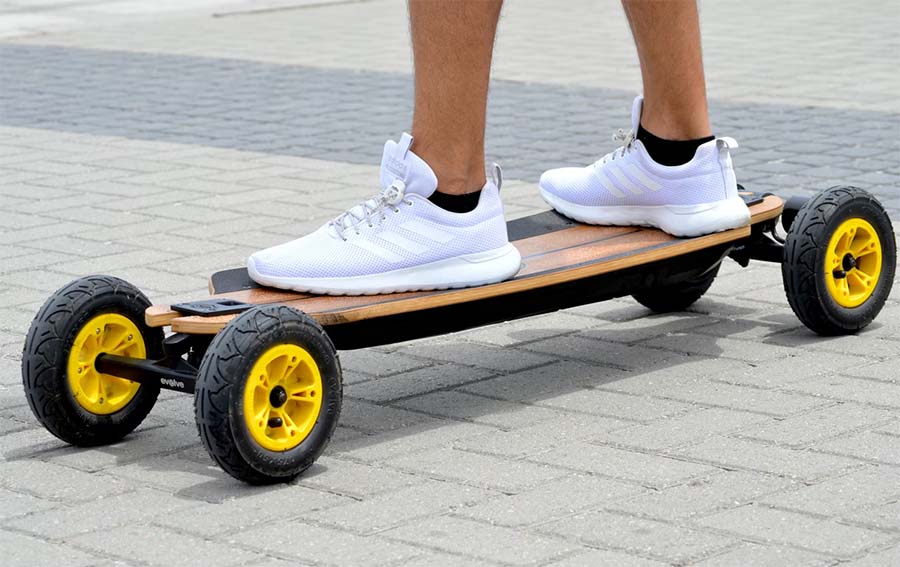 man with white shoes riding with an Evelo skateboard