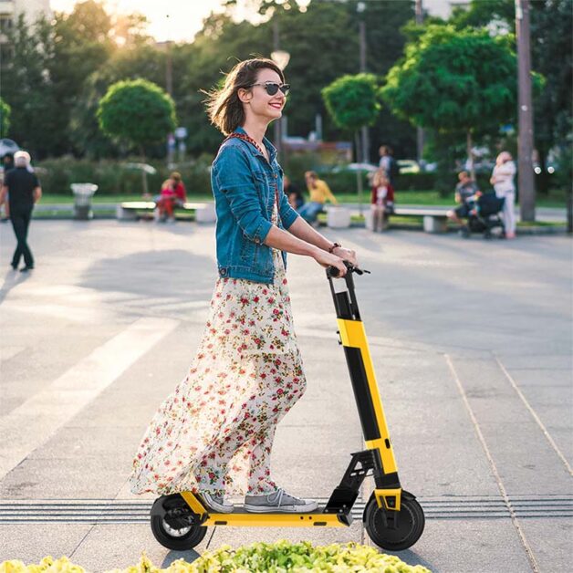 A smiling woman riding with yellow Hiboy NEX5 electric scooter.