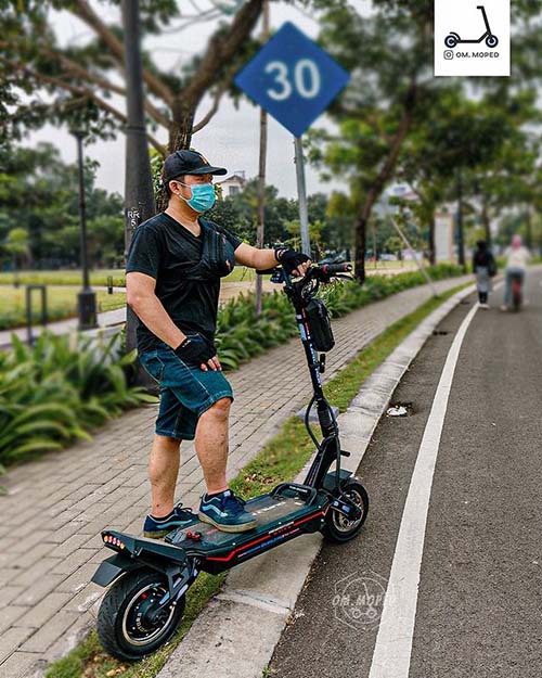 A man is standing next to his Dualtron Storm electric scooter