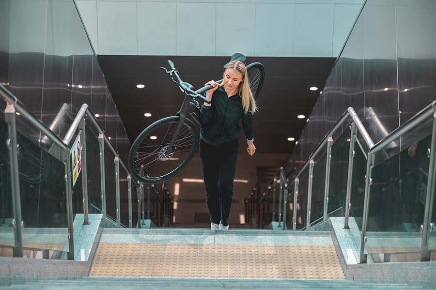 Woman is carrying electric bike up stairs