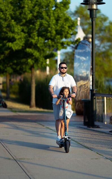 father with daughter riding on one electric scooter