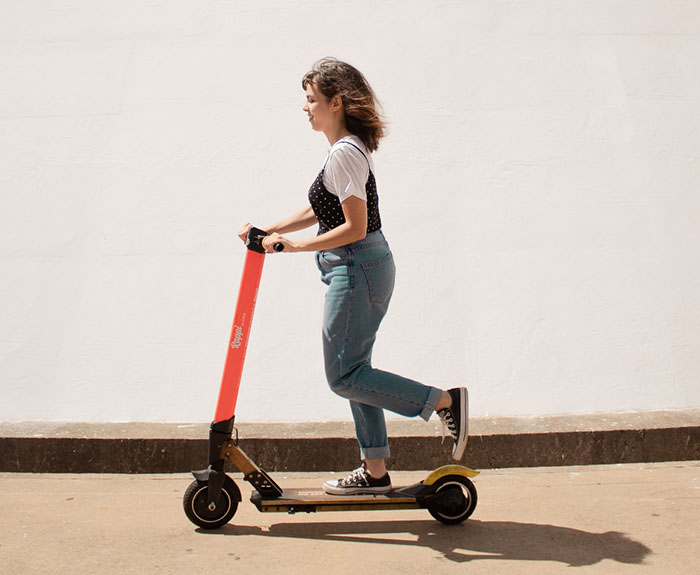 Girl pushing electric scooter with one leg