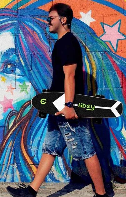 A man is carrying a Hiboy electric skateboard