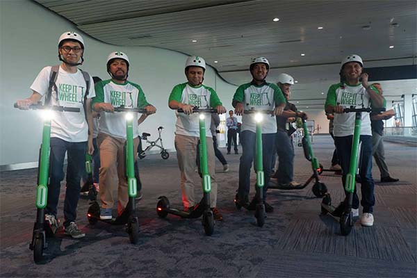 Men with green Grab electric scooters