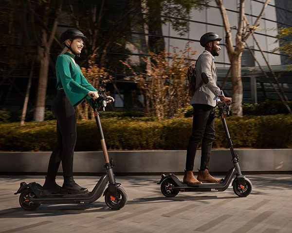 man and woman riding with Niu electric kick scooters