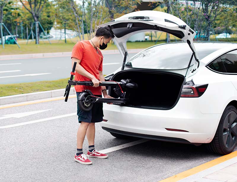 man fitting an electric scooter to the trunk of the car