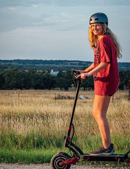 girl with a helmet riding an electric scooter