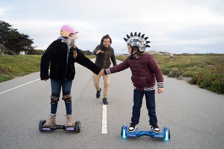 kids riding with gyroor hoverboard and father is chasing them