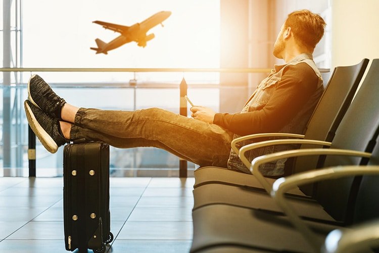 man siting in airport terminal with a hoverboard in his suitcase.