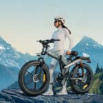 woman is standing on the top of the mountain with her new engwe x26 e-bike