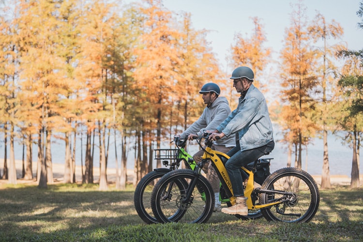 two men riding electric bikes in the forest