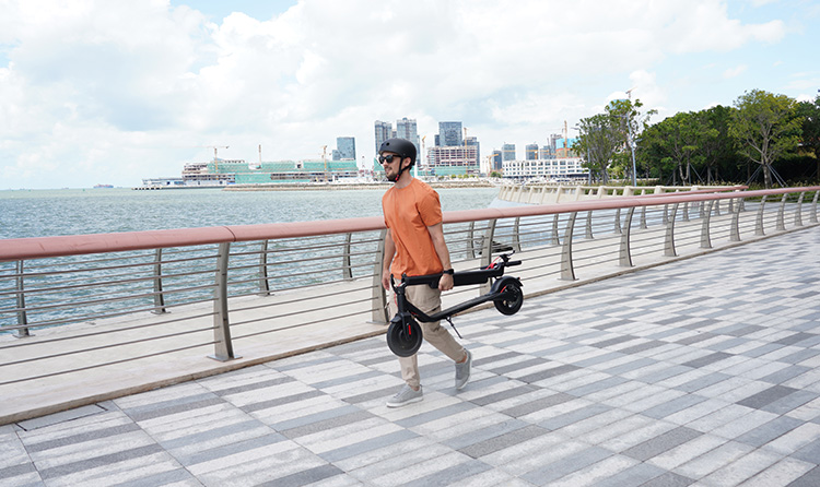man carrying a folded electric scooter