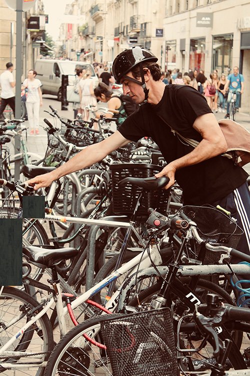 man parking his e-bike in a crowded area next to other bicycles