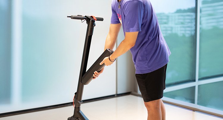 man attaching a battery to electric scooter.