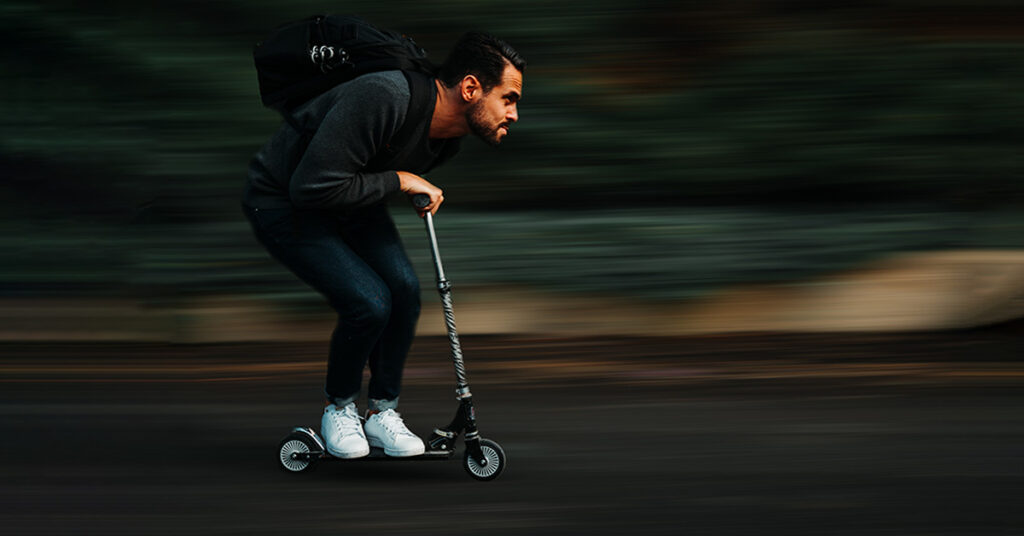 funny image of man riding a kids electric scooter