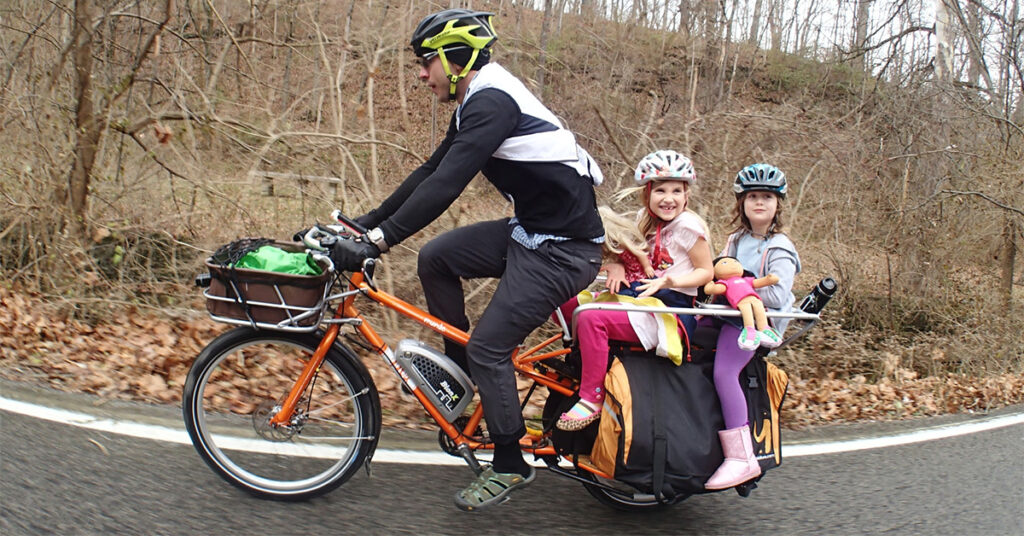 man is hauling his kids with electric cargo bike