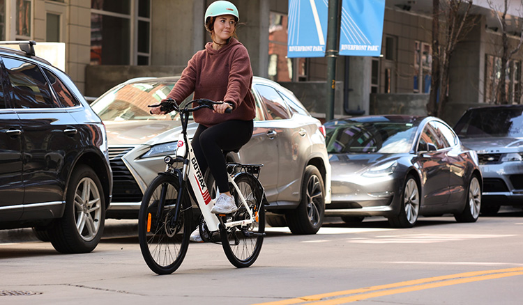 woman with helmet riding a gotrax electric bike in the city