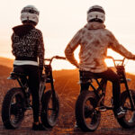 man and woman enjoying a sunset while riding electric bikes
