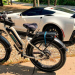 white magicycle fat tire electric bike in front of the white sports car