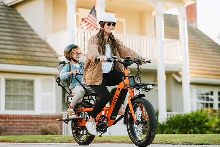 woman riding with KBO cargo e-bike with kid sitting on the rear rack