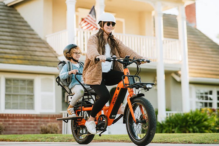 woman riding with KBO cargo e-bike with kid sitting on the rear rack