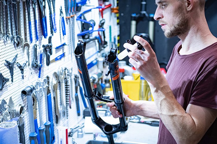 bicycle mechanic checks front suspension fork