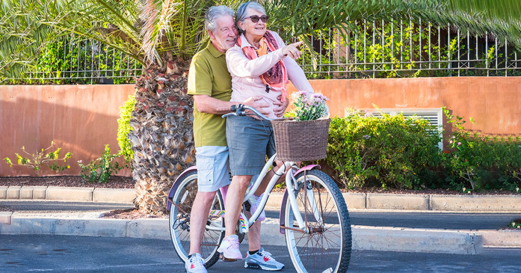 elderly couple sitting on a same electric bike and hugging