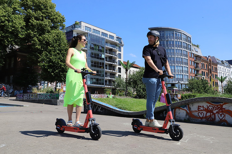 man and woman riding electric scooters