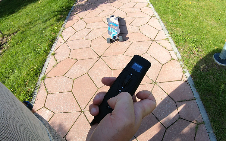 man demonstrating a remote control of an electric skateboard