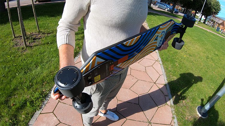 man holding an electric skateboard and showing its motors